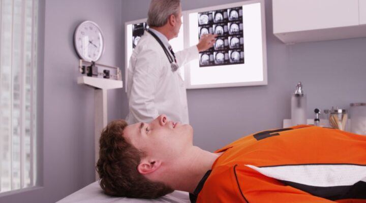 young athlete on doctor's table as doctor reviews his skull x rays